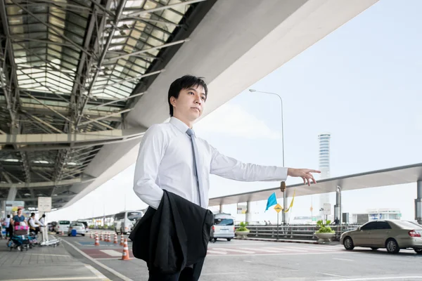 Business travel concept - Young Asian business man calling taxi