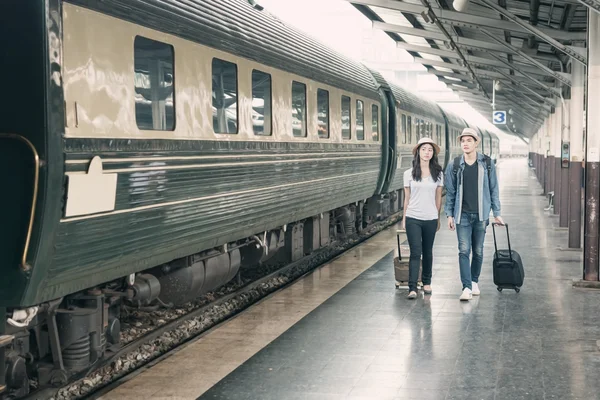 Couple of Asian tourists waiting train in station