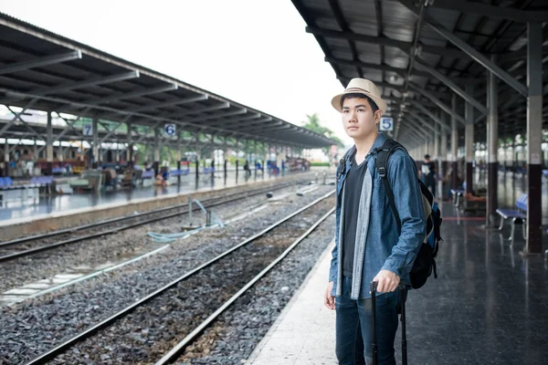 Asian young man waiting train at station