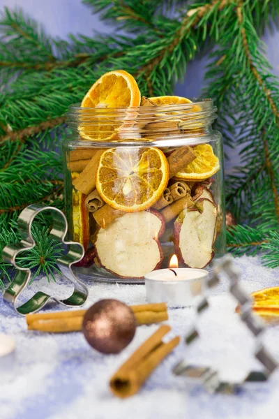 Christmas decoration. Fir tree, snow, candles, metal molds for Christmas cookies and jar with dried oranges, dried apples, cinnamon (selective focus)