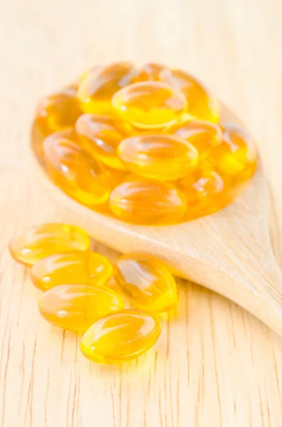 Fish oil capsules in wooden spoon.