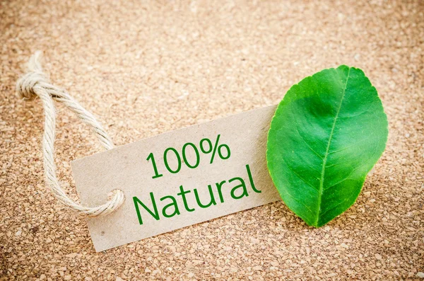 100% Natural word on recycle brown tag with green leaf.