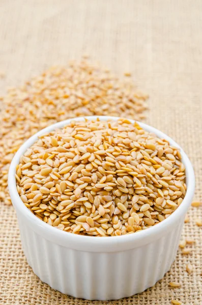 Heap of gold linseed or flax seeds in white cup.