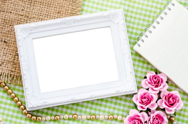 Blank vintage white photo frame and open diary with pink rose on