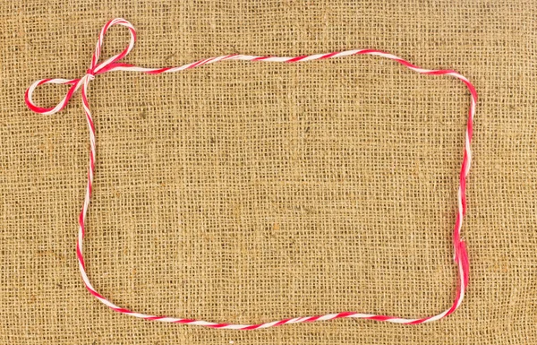 Red and white bow rope frame on brown hemp