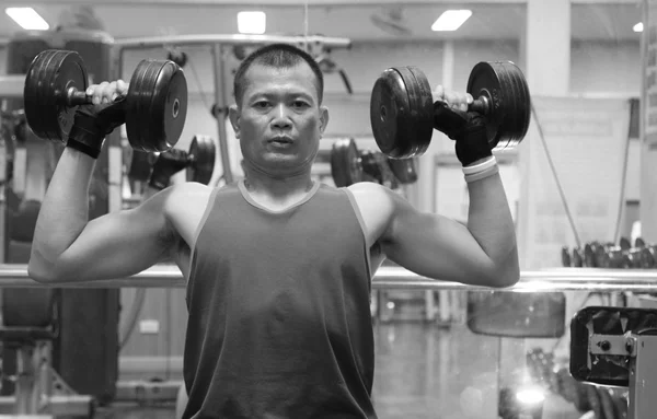 Exercising in the gym, Strong man lifting hand weights.Black and