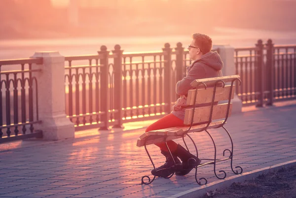 Lonely Man Sitting on a Bench during Sunset. Young Man Sitting o