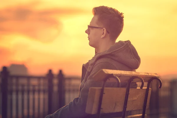 Lonely Man Sitting on a Bench during Sunset. Portrait of Young M