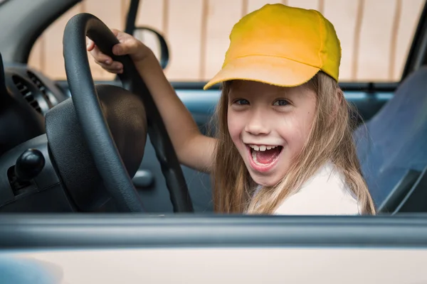 Portrait of a cheerful little girl at the wheel the car