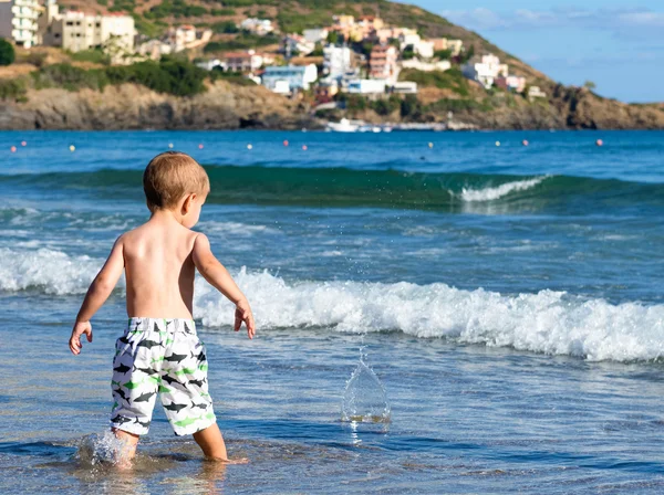 Child on the beach throwing stones into the water.