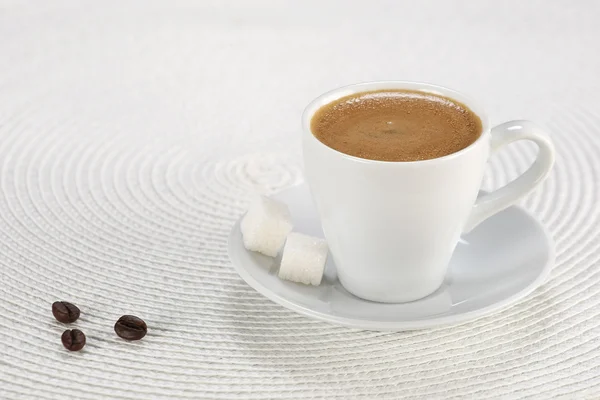 Cup of coffee, sugar cubes on a white wicker a mat
