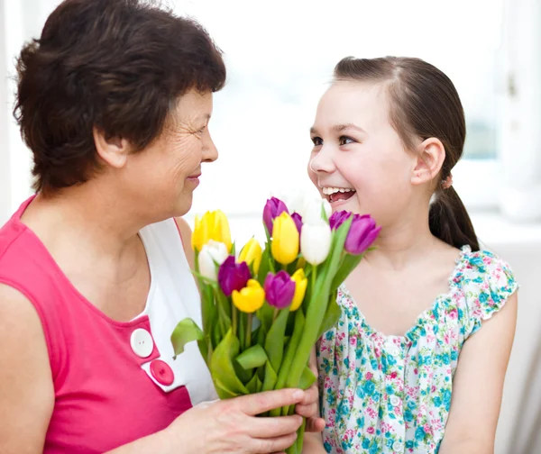 Grandmother with granddaughter. Woman and child with bouquet of flowers