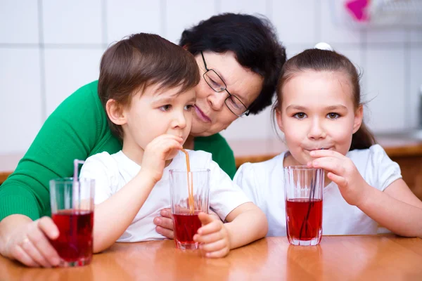 Grandmother with her grandchildren drink juice