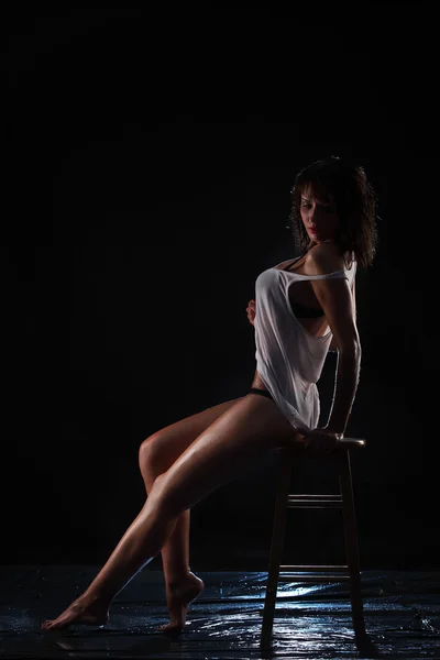 Young sexy nude woman wet sitting on chair. Water studio photo.
