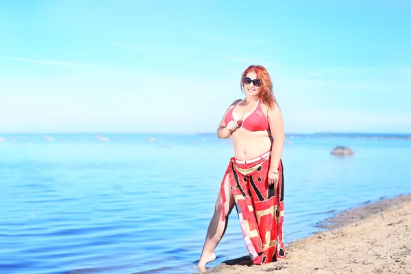 Red-haired plus size woman resting on coast
