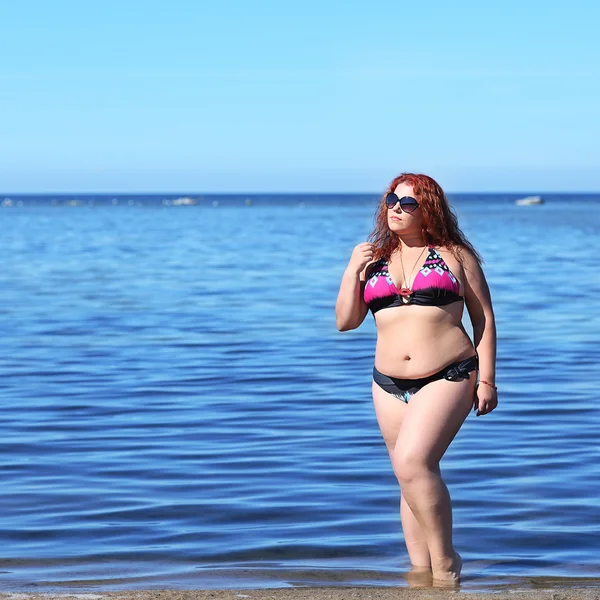 Red-haired plus size woman resting on coast