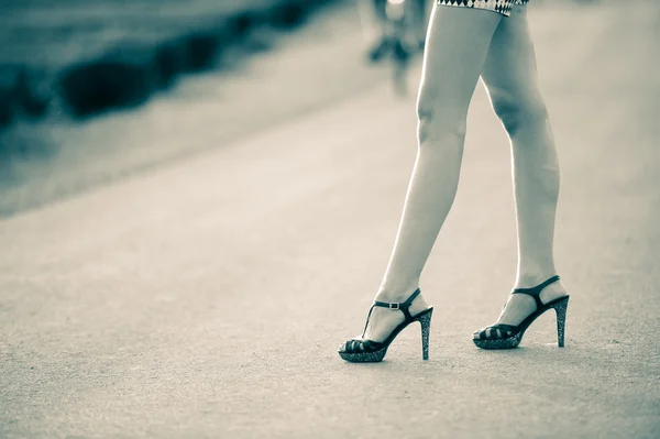 Beautiful woman legs in high heel shoes on the road