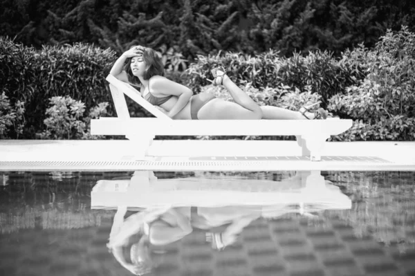 Black and white bikini asia woman on sunbath longue by the pool