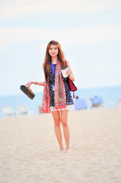 Asia beautiful woman on the beach, hold iced coffee and shoes