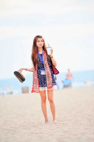 Asia beautiful woman on the beach, hold iced coffee and shoes