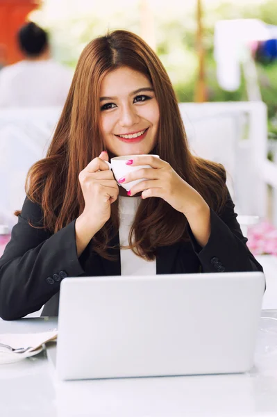 Asia young business woman sitting in cafe with laptop and coffe