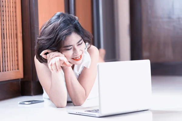 Happy asia woman Lying on Floor with Laptop at home