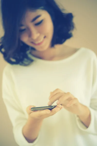 Asia Young beautiful woman writes SMS to mobile phone