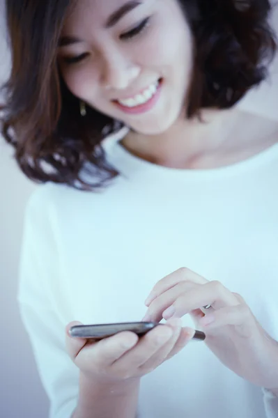 Asia Young beautiful woman writes SMS to mobile phone