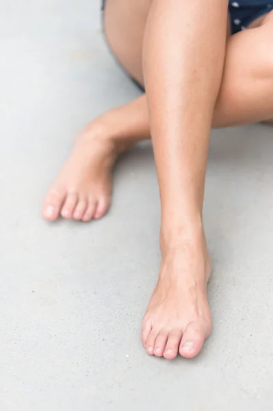 Asia woman sitting on  floor. Feet close up. Blurred background.