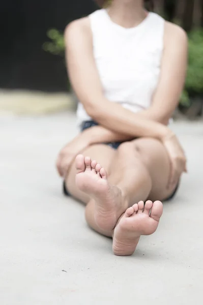 Asia woman sitting on  floor. Feet close up. Blurred background.