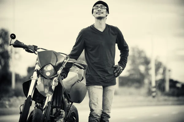 Portrait of man biker standing on road with motorcycle