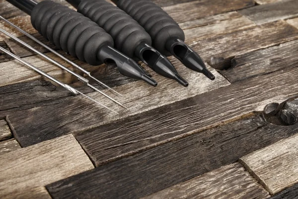 Tattoo needles on wooden background.