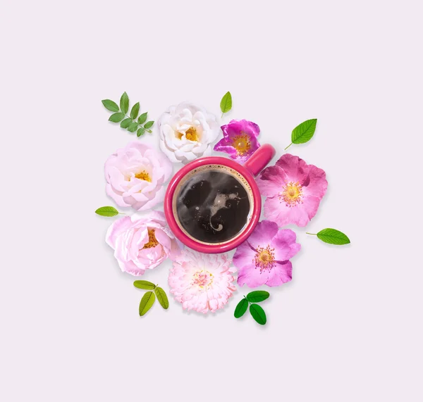Pink and white wild roses around cup of coffee. Flat lay