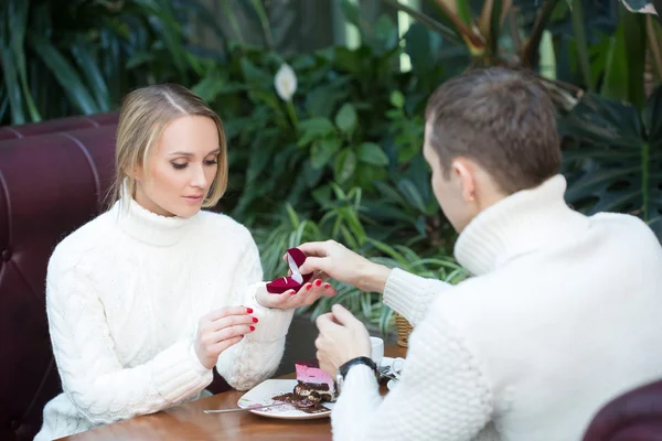 Restaurant, couple and holiday concept - excited young woman looking at boyfriend with engagement ring