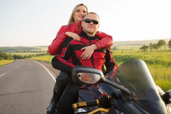 Biker man and woman sitting on a motorcycle.