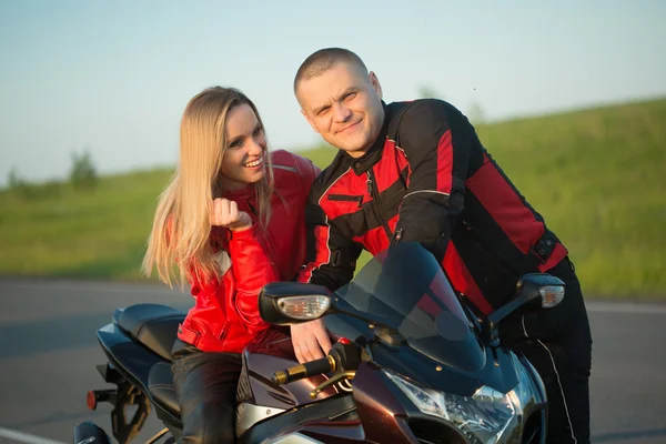 Biker man and woman sitting on a motorcycle.