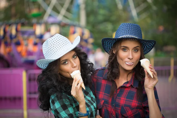 Two beautiful girls in cowboy hats eating ice cream