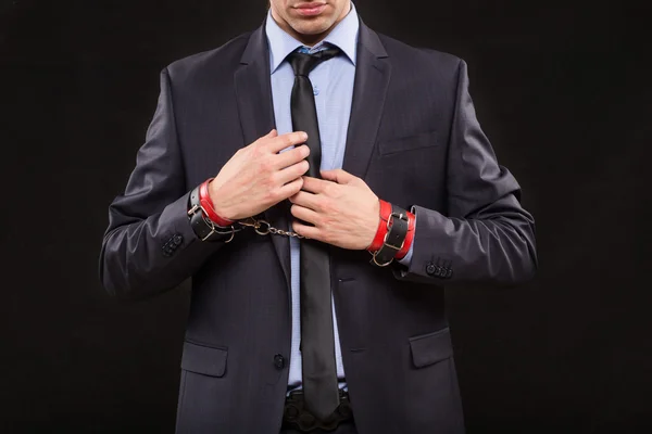 Man in a business suit with chained hands. handcuffs for sex games