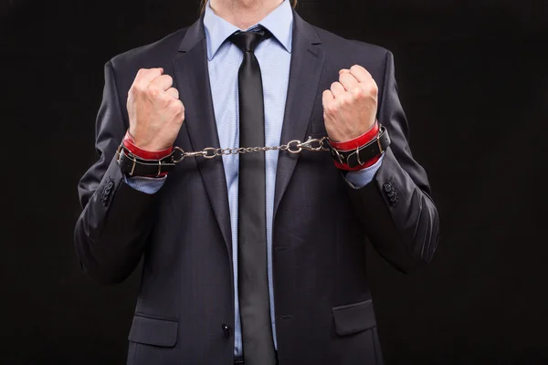 Man in a business suit with chained hands. handcuffs for sex games