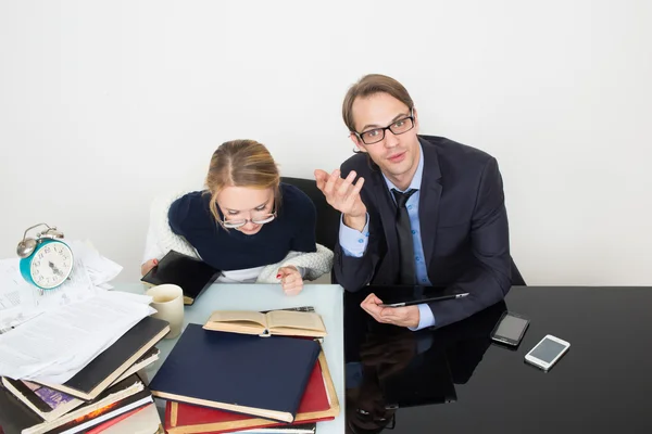 Office. woman looking for information in books. The man speaks on the phone