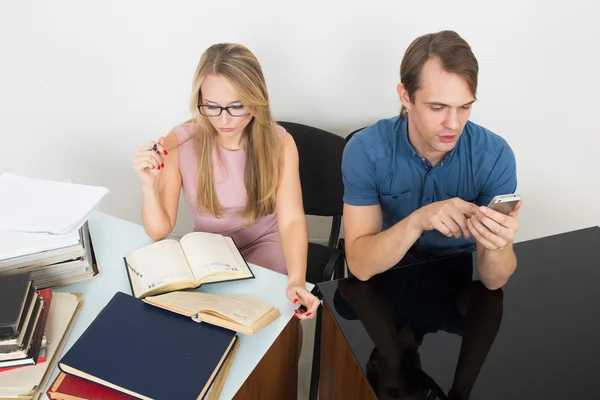 Library. woman looking for information in books. The man speaks on the phone