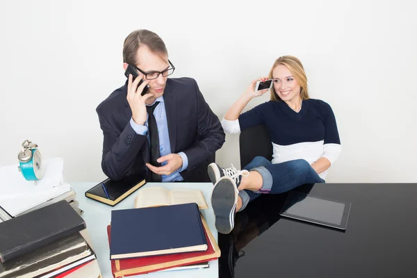 Woman prevents a man to work. talking phone. It distracts from business. feet on table