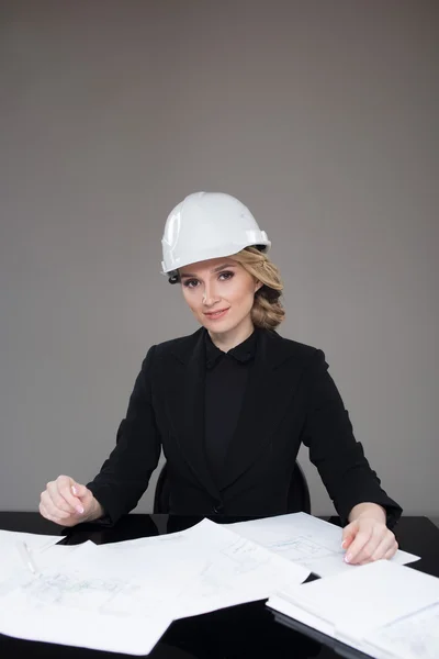 Woman architect with drawings. Beautiful girl in a building helmet