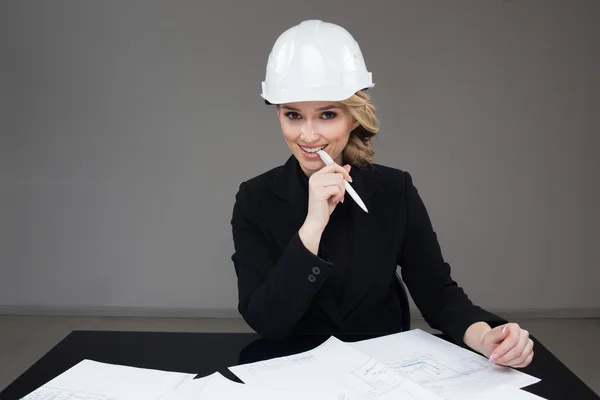 Woman architect with drawings. Beautiful girl in a building helmet