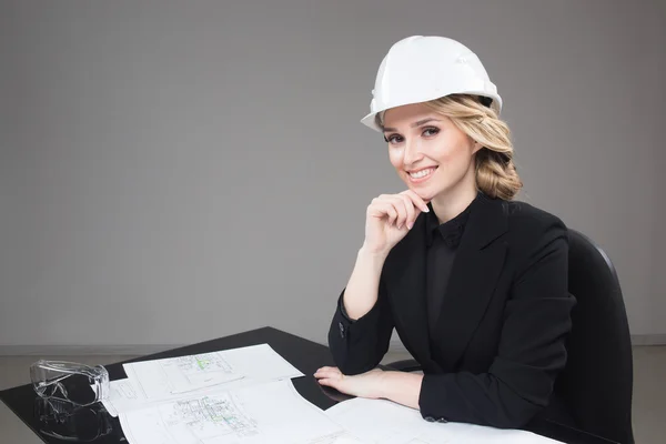Woman architect with drawings. Beautiful girl in a building helmet