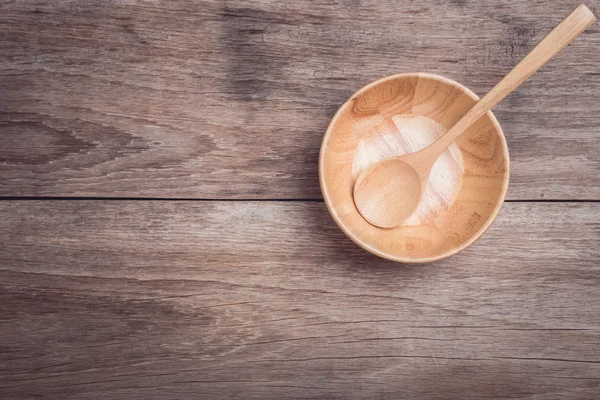 Wooden bowl with spoon on wooden table top view