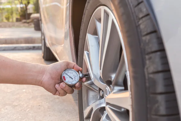Man holding pressure gauge and checking air pressure of the car