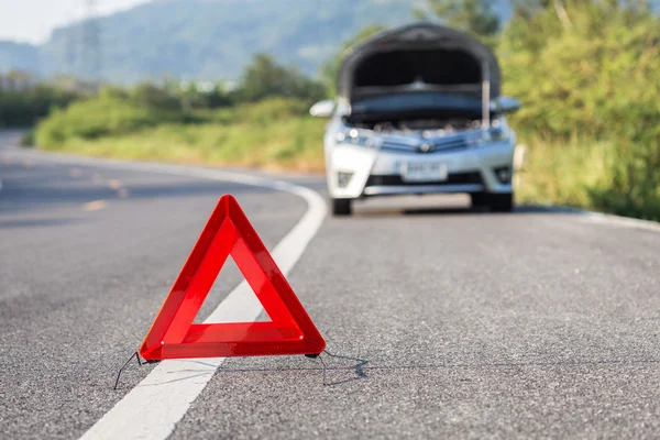 Red emergency stop sign and broken car on the road