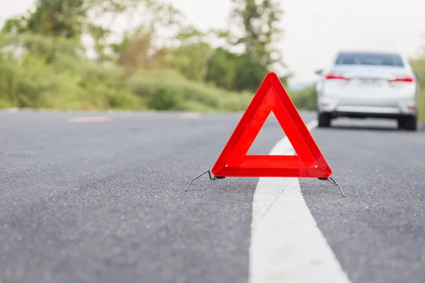 Red emergency stop sign and broken car on the road