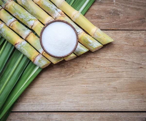 Top view white sugar and sugar cane and leaf on wooden